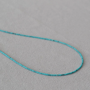 Détail de perles de turquoise ultra-fines aux textures naturelles et design minimaliste