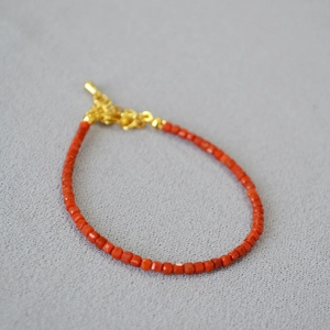 Detailed macro view of square red agate beads with a gold lobster clasp and extension chain