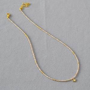 Détail du collier de perles champagne avec pendentif étoile dorée et fermoir mousqueton