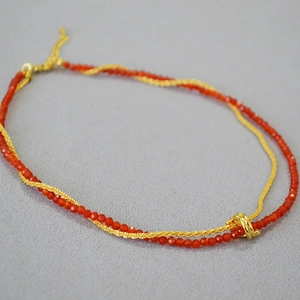 Close-up of double-layer necklace with red agate beads and a twisted gold chain link