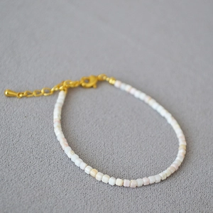 Gros plan d'un collier en perles de coquillage rose avec fermoir mousqueton doré et chaîne