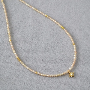 Détail du collier de perles champagne avec pendentif étoile dorée étincelante et cristal blanc