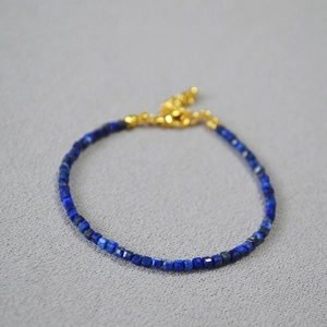 Dettaglio di perle quadrate di lapis blu su bracciale con chiusura dorata