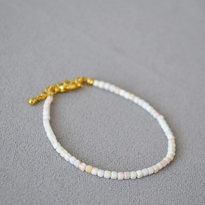 Détail de perles carrées roses et blanches avec fermoir mousqueton doré et chaînette