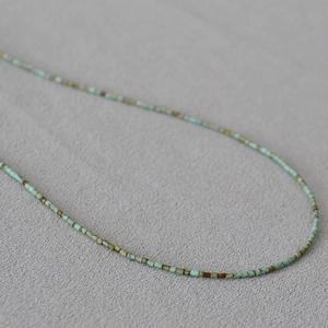 Vue macro du collier de perles turquoise et brunes ultra-fines avec texture de pierre