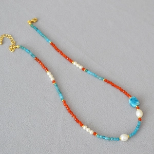 Close-up of beaded necklace with blue raw stone, pearls and gold lobster clasp