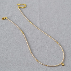 Détail du collier avec perles champagne, pendentif étoile et fermoir mousqueton