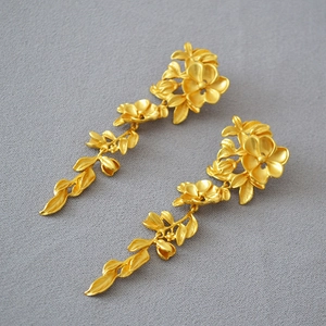 Detail of vintage gold plated brass floral drop earrings with a matte textured finish