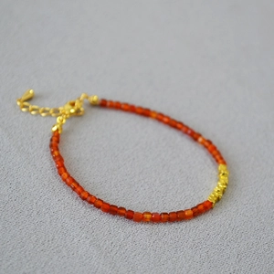 Close-up of red agate beaded bracelet with gold faceted metal accents and lobster clasp