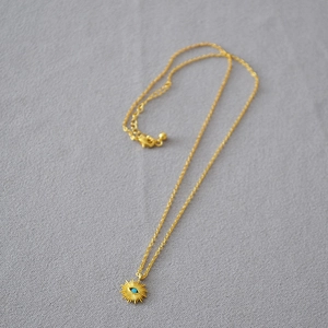 Détail du collier pendentif soleil doré avec perle turquoise et chaîne ajustable