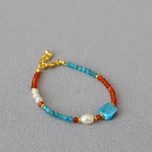 Detail of beaded necklace with blue turquoise, red agate stones, and white pearls