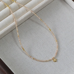 Vue macro du collier perlé avec pendentif étoile en zircon champagne sur l'écrin