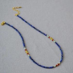 Detailed view of beaded necklace with lapis lazuli, red agate, and golden lobster clasp