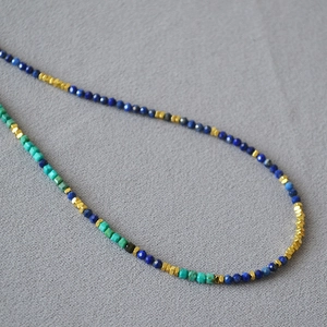 Detail of beaded necklace with lapis lazuli and irregular silver chips on fabric