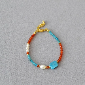 Agate and apatite beaded necklace with gold clasp on textured background
