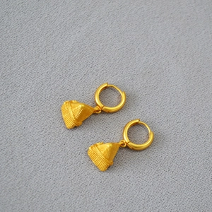Macro detail of gold Zongzi charms with woven texture on minimalist hoop earrings