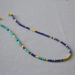 Close-up of lapis lazuli and turquoise beaded necklace with irregular gold accents