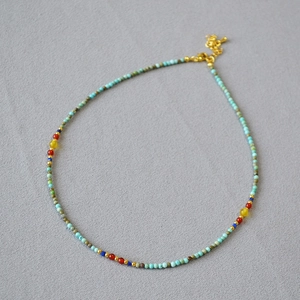 Close-up of handmade turquoise beaded necklace with colorful stones and gold clasp