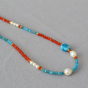 Macro shot of handmade beaded necklace with natural red agate, pearls and blue stones