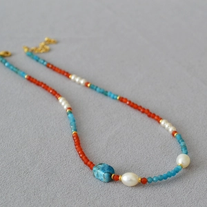 Macro detail of handmade beaded necklace with red agate, blue apatite, and pearls
