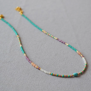 Detail of beaded turquoise and purple lepidolite necklace with gold lobster clasp