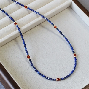 Macro view of blue lapis lazuli and red agate beaded necklace with gold metal accents