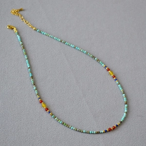 Detail of colorful beaded necklace with turquoise stones and gold lobster clasp