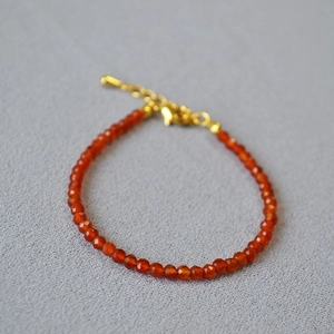 Macro shot of faceted red agate beads on a delicate chain with a gold lobster clasp