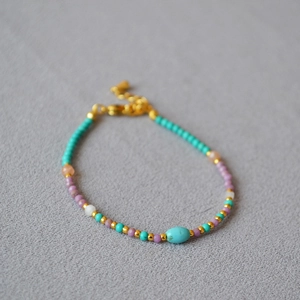 Close-up of beaded necklace with turquoise, purple mica beads and gold lobster clasp
