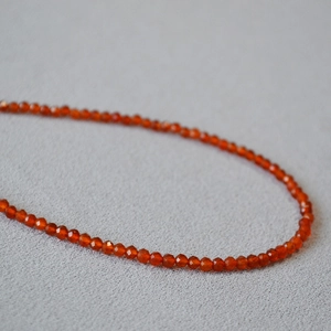 Macro detail of faceted red agate beads on a minimalist necklace with polished texture