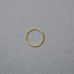 Close-up of minimalist thin gold ring band on textured dark grey stone surface