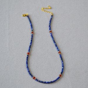 Detailed macro view of lapis lazuli beads with red agate accents and golden clasp
