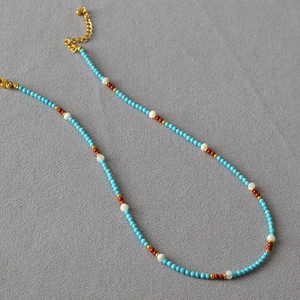 Minimalist boho necklace with turquoise beads and golden metal spacers on grey texture