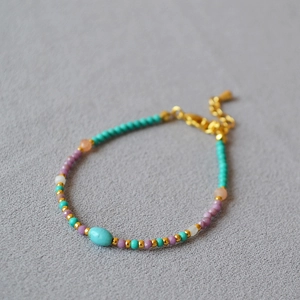 Close-up of lavender bead necklace with turquoise stone and golden lobster clasp detail