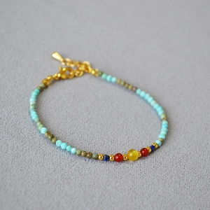 Ethnic bohemian beaded necklace with turquoise and agate stones on gray textured background