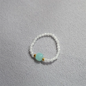 Handmade beaded sugar cube ring with blue crystal bead and gold accents on gray background