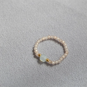 Macro shot of handmade beaded ring with light blue rectangular stone and golden beads