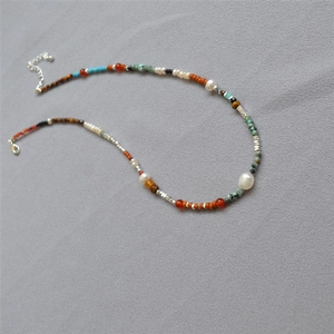 Détail d'un collier bohème avec turquoise, perles d'eau douce et perles d'agate rouge