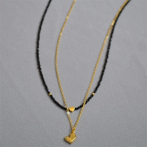 Détail du collier à perles noires et pendentif coeur en or orné d'un petit diamant