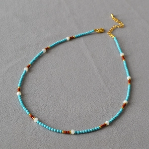 Detailed view of turquoise and shell beaded necklace with gold lobster clasp and chain