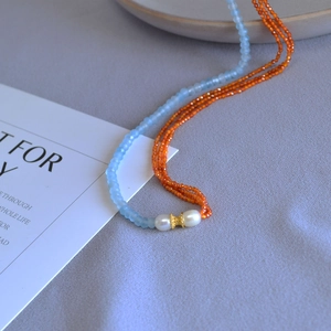 Blue faceted stone and orange beaded necklace with white pearls and gold metal accents