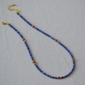 Detail of beaded necklace with blue lapis lazuli, red agate beads and gold clasp