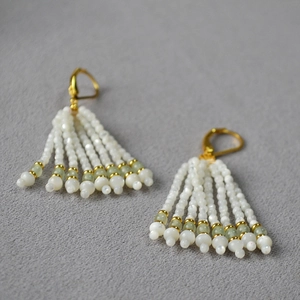 Détail de boucles d'oreilles à pompon avec perles de coquillage et turquoises
