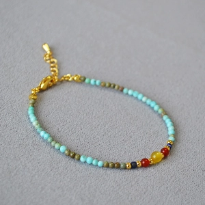 Detail of bohemian turquoise beaded bracelet with yellow gemstone and gold clasp