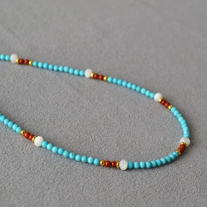 Detailed view of handmade beaded necklace with turquoise, shell, and gold-tone spacers