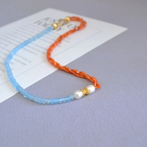 Detail of beaded necklace with blue faceted stones, pearls, and gold metal clasp
