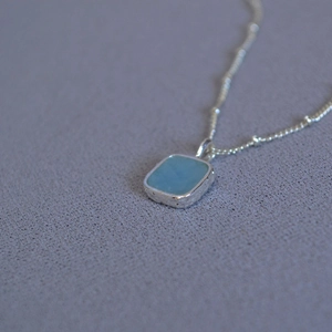 Minimalist silver necklace featuring a geometric square light blue aquamarine stone pendant