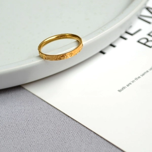 Detailed view of golden hammered ring with dragon scale texture on white ceramic