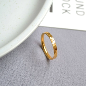 Macro shot of gold dragon scale textured thin ring showcasing reflective surface details