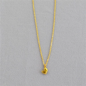 Détail d'un pendentif coeur doré aux facettes géométriques sur une chaîne fine